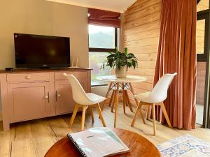 a living room with a tv and a table and chairs at Heuwelsig Farm Cottages in Franschhoek