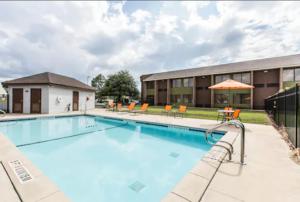 a swimming pool with chairs and a building at Comfort Inn Warner Robins - Robins Air Force Base Area in Warner Robins