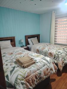 two beds in a bedroom with blue walls at Casa Isidora in Toltén