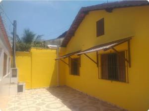 a yellow building with windows and a roof at Quartos para locação in Mongaguá