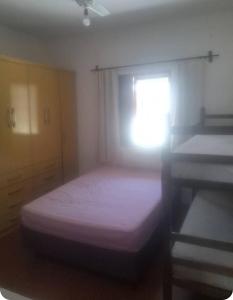 a small bedroom with a bed and a window at Quartos para locação in Mongaguá