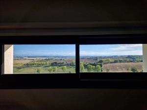 a window with a view of a field through it at Chambre indépendante Pyrenées in Lombez