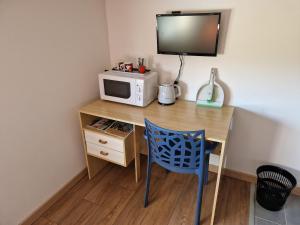 a desk with a microwave and a blue chair at Chambre indépendante Pyrenées in Lombez