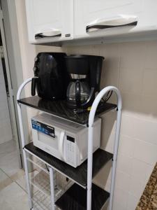 a microwave on a shelf in a kitchen at Tranquility with convenience in Caxambú Tranquilo in Caxambu