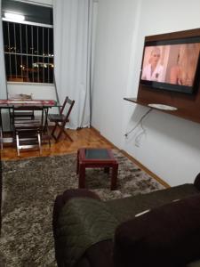 a living room with a couch and a tv on a wall at Tranquility with convenience in Caxambú Tranquilo in Caxambu