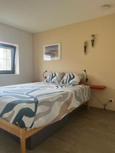 a bedroom with a bed with a blue and white comforter at Bellefleur Cottage in Herent