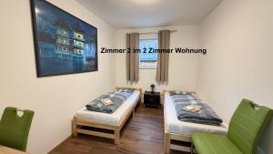 two beds in a room with two green chairs at Kim Ferienwohnung B in Sömmerda