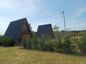 two houses with black roofs in a field at Cabañas Amapola del 66 in Miramar