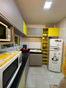 a kitchen with a white refrigerator and yellow cabinets at Casa Maresia Ponta da Asa in Coruripe