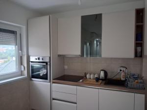 a kitchen with white cabinets and a sink and a window at Onix 1 in Soko Banja