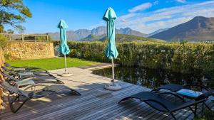 a group of chairs and umbrellas on a wooden deck at Heuwelsig Farm Cottages in Franschhoek