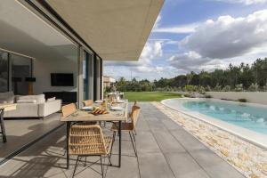 a patio with a table and chairs next to a swimming pool at Lagoon Residence 56 Deluxe in Óbidos