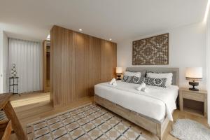 a bedroom with a white bed and a wooden wall at Lagoon Residence 56 Deluxe in Óbidos