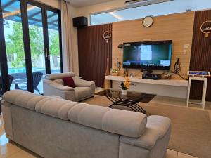 a living room with a couch and a tv at One Summerday in Desaru in Kangkar Chemaran