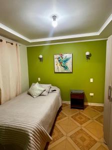a bedroom with green walls and a bed at Acogedora casa para 6 personas en algarrobo in Algarrobo