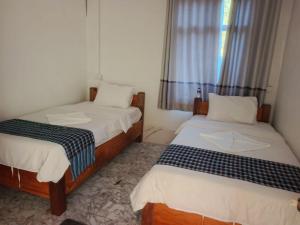 two beds in a small room with a window at Khamfong Guesthouse in Pakbeng