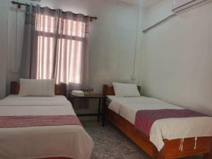 two beds in a room with a window at Khamfong Guesthouse in Pakbeng