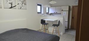 a bedroom with a bed and a kitchen with two stools at Ferienwohnung PfalzRide in Annweiler am Trifels