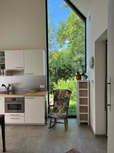 a kitchen with white cabinets and a chair and a window at Bellefleur Cottage in Herent