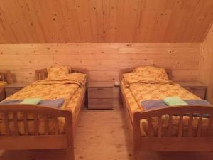 a room with two beds in a log cabin at Hargitaház Mountain House in Harghita-Băi