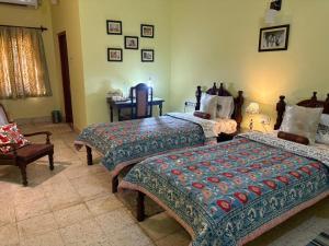 a bedroom with two beds and a chair at Udai Niwas - Bikaner in Bikaner