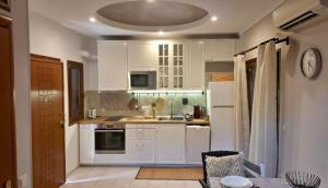 a kitchen with white cabinets and a clock on the wall at Beach house IvMare in Ierissos