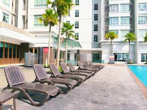 a row of chaise lounge chairs next to a swimming pool at peacehome 13a in Cyberjaya