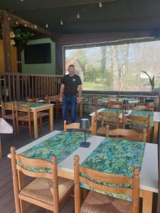 a man standing in a room with tables and chairs at La Charrue in Vieux-Mareuil