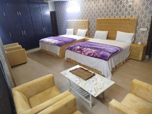 a hotel room with two beds and a couch at Grand Orchard One Hotel in Lahore