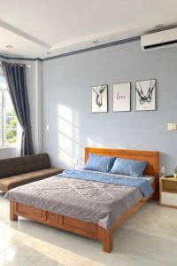 a bedroom with a bed and a couch at PINK Hotel Cần Thơ in Can Tho
