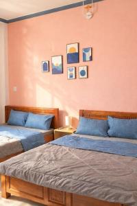 two beds in a room with paintings on the wall at PINK Hotel Cần Thơ in Can Tho