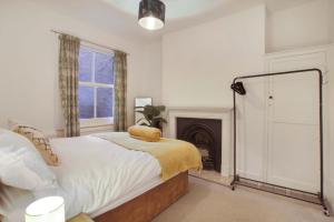 a white bedroom with a bed and a fireplace at town house in Northampton