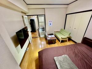 a bedroom with a bed and a green chair at Stay Plus Sophia in Utsunomiya
