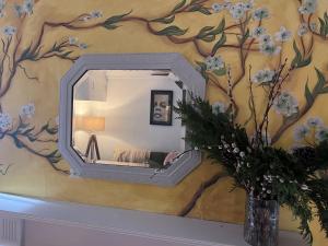 a mirror on a wall with a tree mural at Little B - Artist owned boutique apartment near Southsea beach in Portsmouth +6 photos