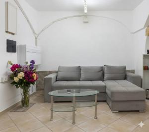 a living room with a couch and a vase of flowers at Sa domu pitticca Cavour in Cagliari