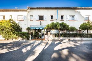 a large white building with trees in front of it at Hotel Oasis in Argelès-sur-Mer