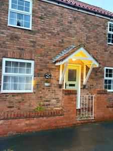 a brick house with a yellow door and windows at Chapel Bricks in Withernwick