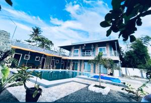 a house with a swimming pool in front of it at Brandons Beach Resort in Inayauan
