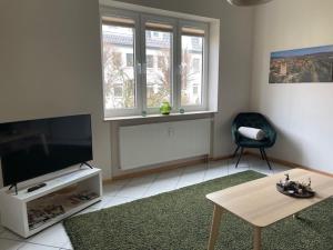 a living room with a flat screen tv and a chair at Ferienwohnung Lahann in Saalfeld