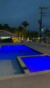 a blue swimming pool at night with at Abricó Beach Hotel in São Sebastião