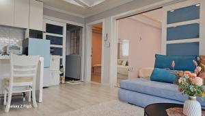 a living room with a blue couch and a kitchen at Pension Haneul Tari in Jeju