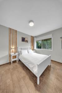 a white bedroom with a large bed and a window at Engel apartments -אירוח למטיילים בגליל עליון in Tsiv'on