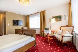 a hotel room with a bed and a chair at Kurhotel & Hotel Mozart in Bad Gastein
