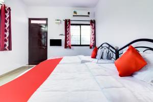 a bedroom with a large white bed with red pillows at Hotel O Omkar Guest House Near Immaculate Conception Church in Panaji