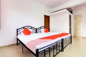 a bedroom with a bed with orange pillows at Hotel O Omkar Guest House Near Immaculate Conception Church in Panaji