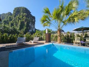 a swimming pool with two chairs and a palm tree at The white mountain pool villa Ao Nang in Ban Thai Thai