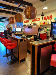 a restaurant with a m taco bar with red chairs at Hotel Anco in Ons Belang