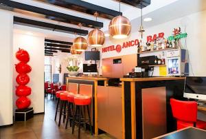 a restaurant with a bar with red stools at Hotel Anco in Ons Belang
