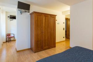a bedroom with a wooden cabinet and a television at Meublè Blue House in Auronzo di Cadore