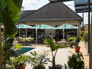 a restaurant with tables and chairs and umbrellas at La Mariette Hôtel & Resort in Kisantu